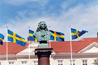 Svenska flaggor med staty i förgrunden